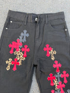 Dark gray denim pants with multicolor cross applique on the front panels.