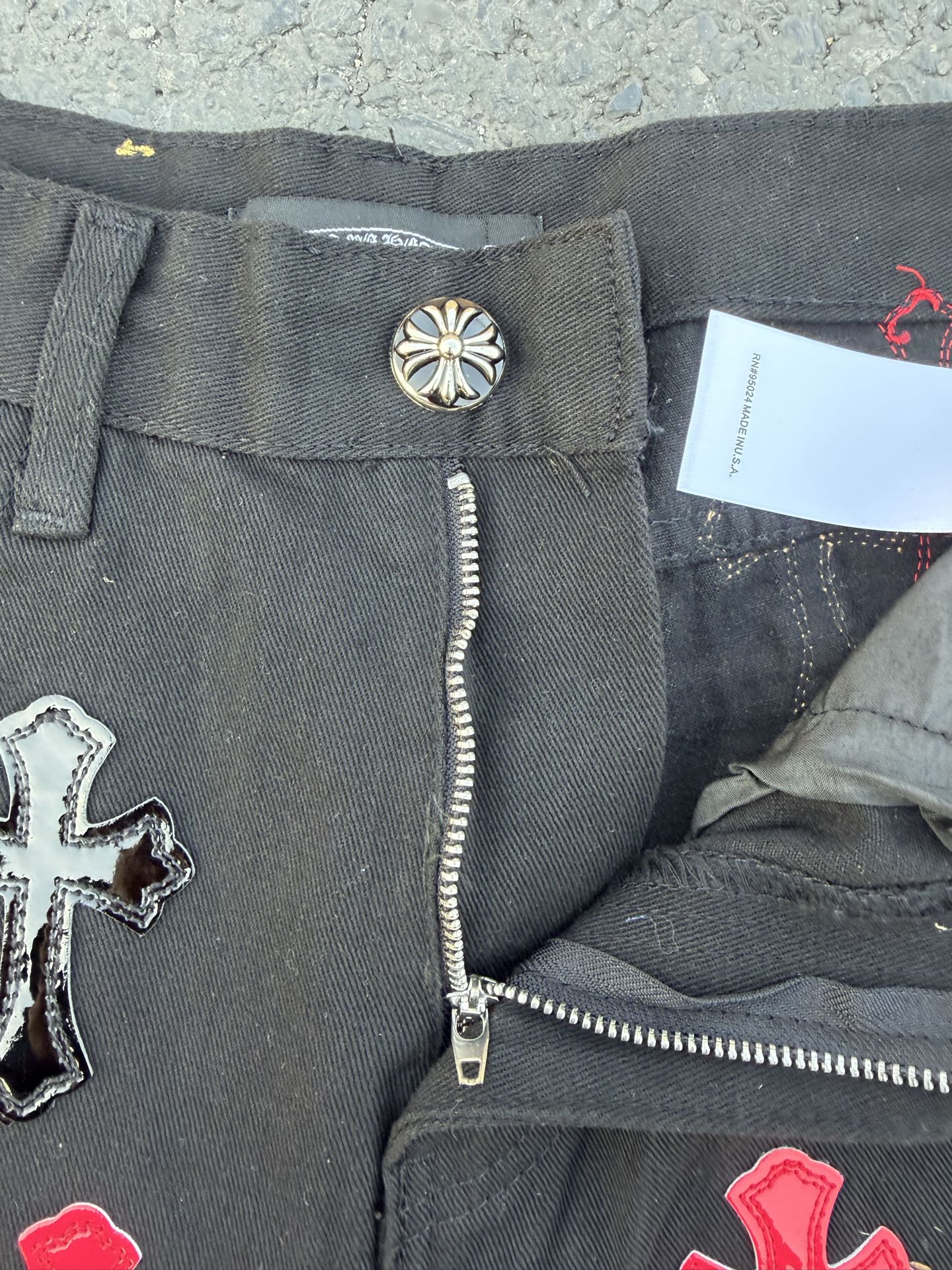 Dark gray denim pants with button closure and exposed zip fly detail near the pocket.