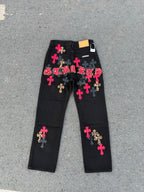 Black denim pants with colorful cross patches and a white tag on the waistband.