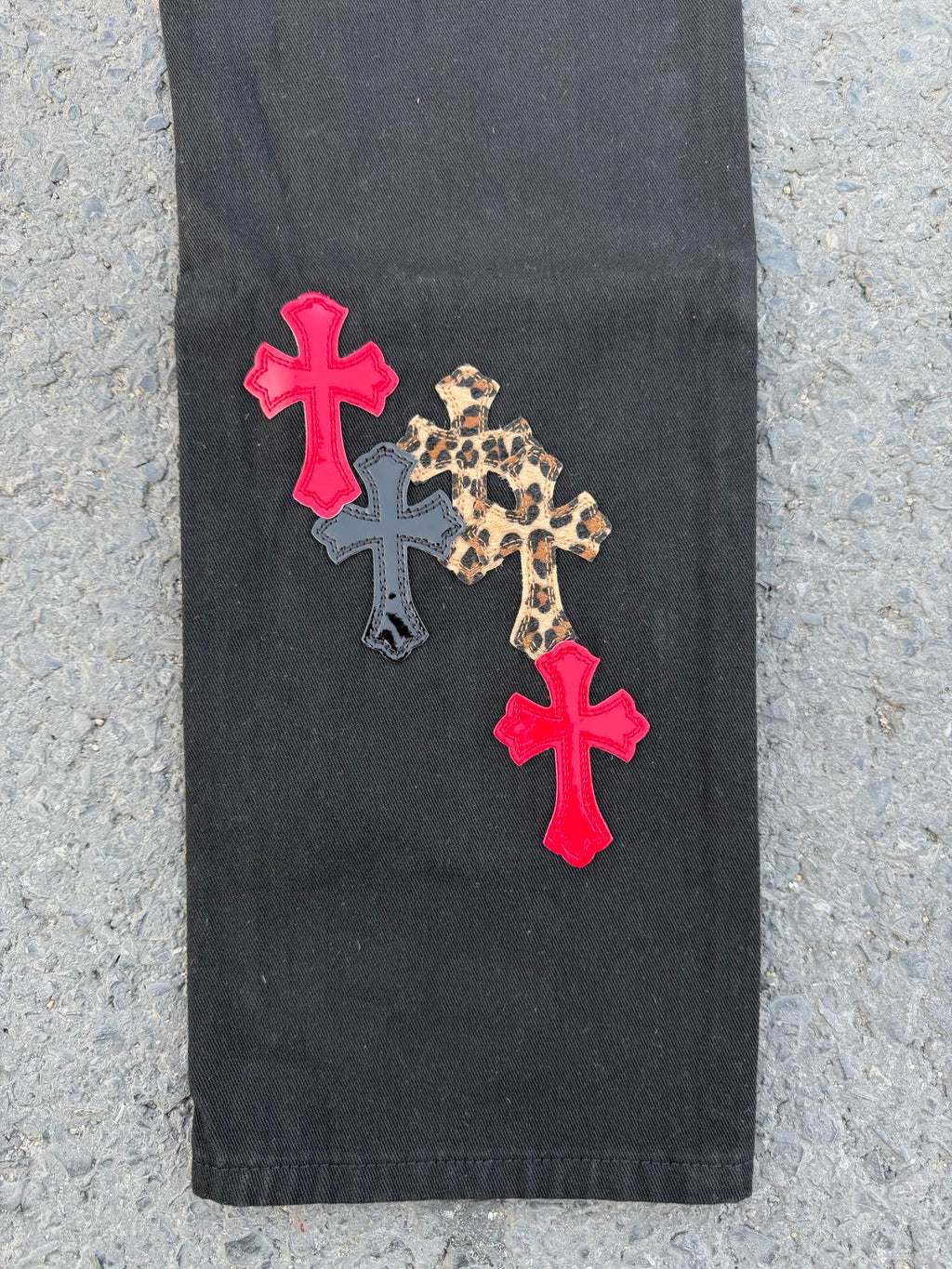 Black pants with two red cross patches and a leopard print cross applique