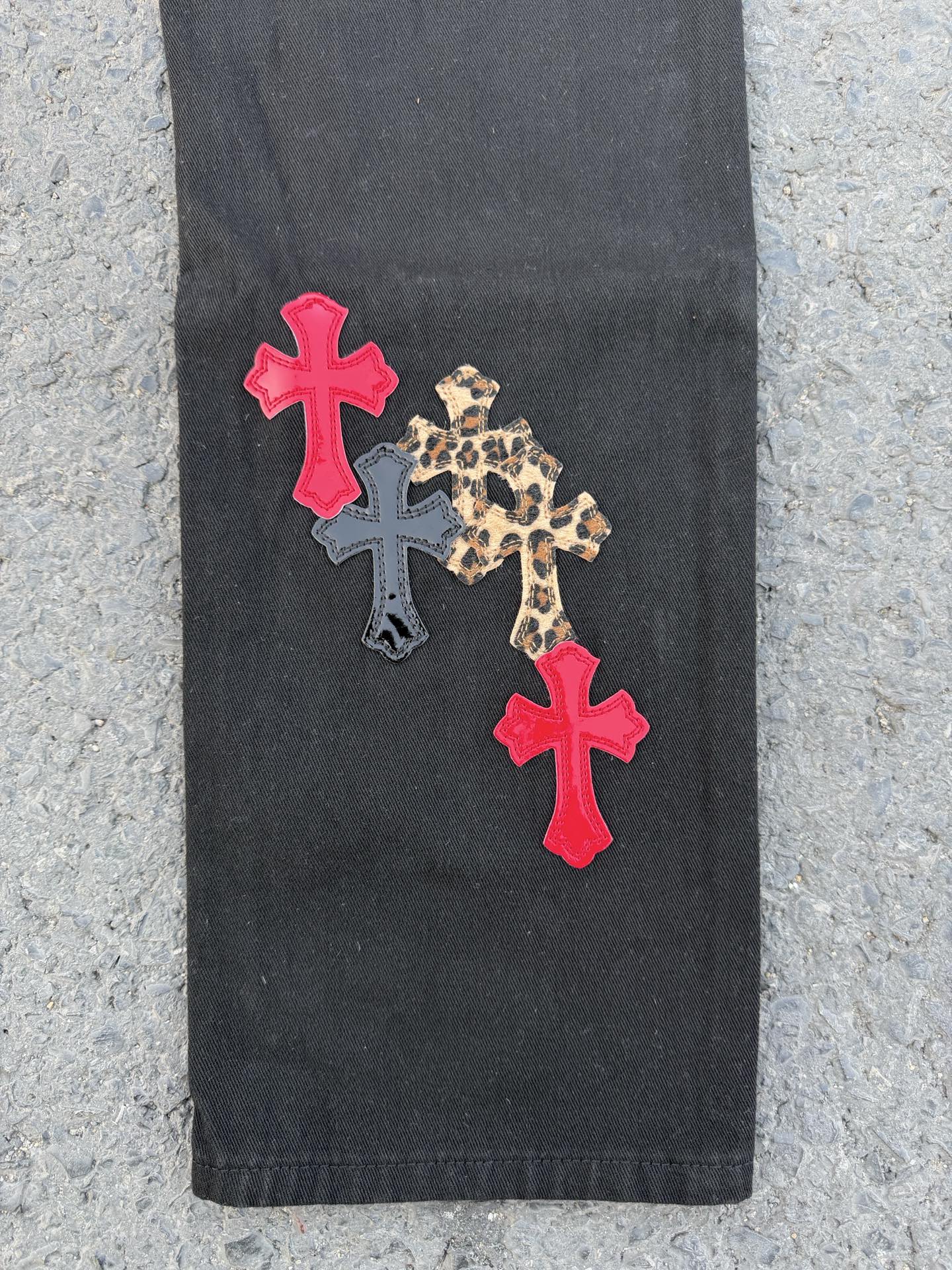 Black pants with two red cross patches and a leopard print cross applique
