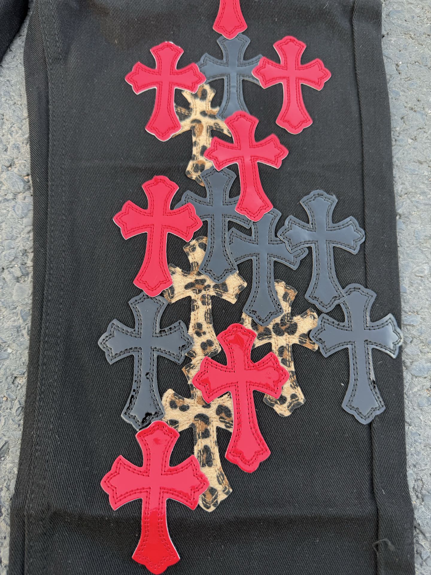 Black pants covered with colorful cross patches in red, blue, and leopard print