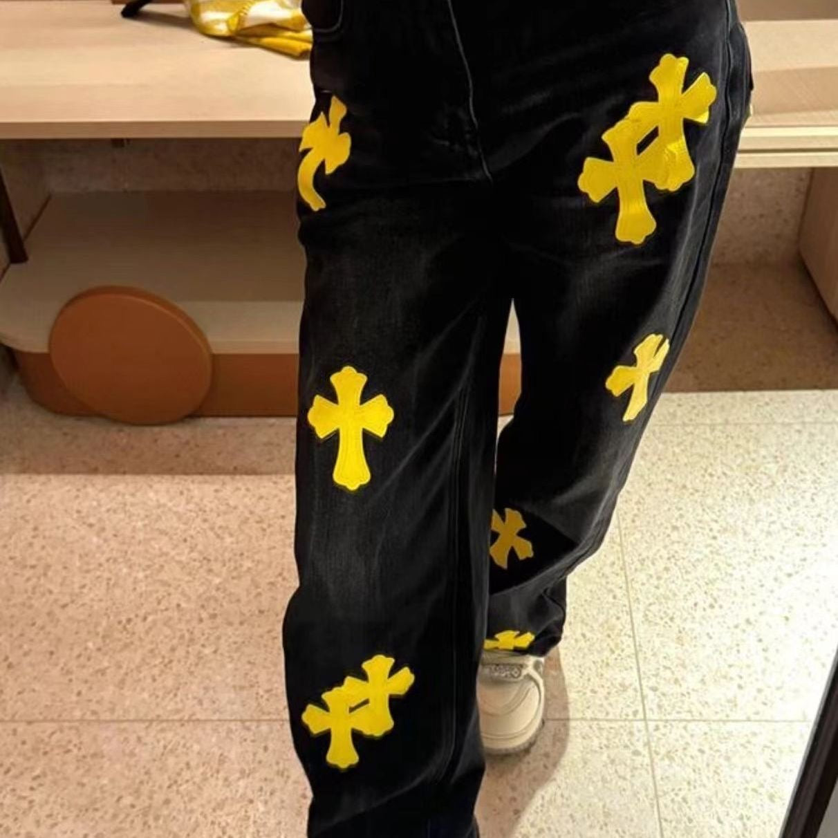 Black pants with yellow cross patches, worn and visible on the legs
