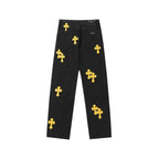 Black denim pants with yellow cross patches and a button fly