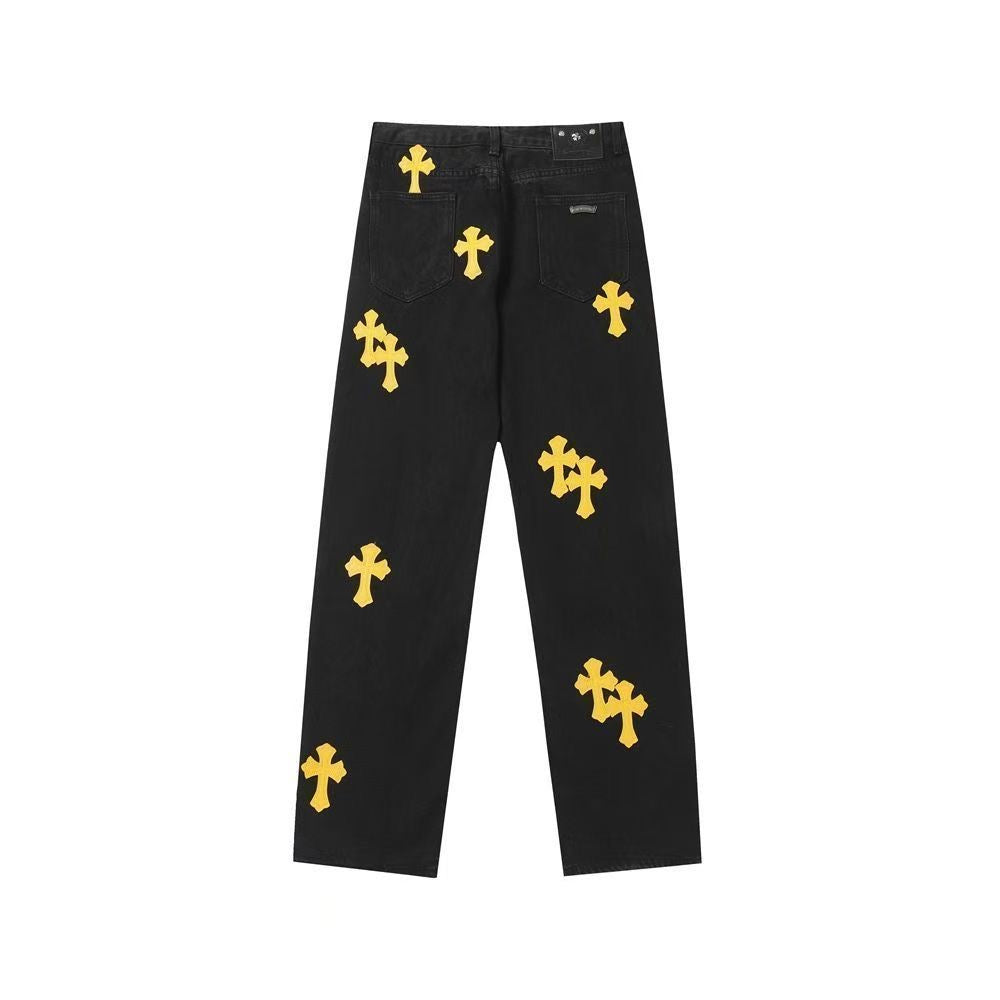 Black denim pants with yellow cross patches and a button fly