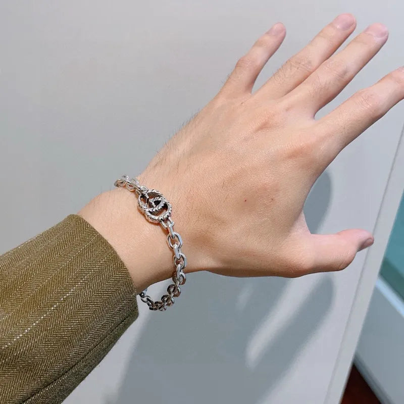 Gucci silver chain bracelet on wrist, round logo charm with curb-style links