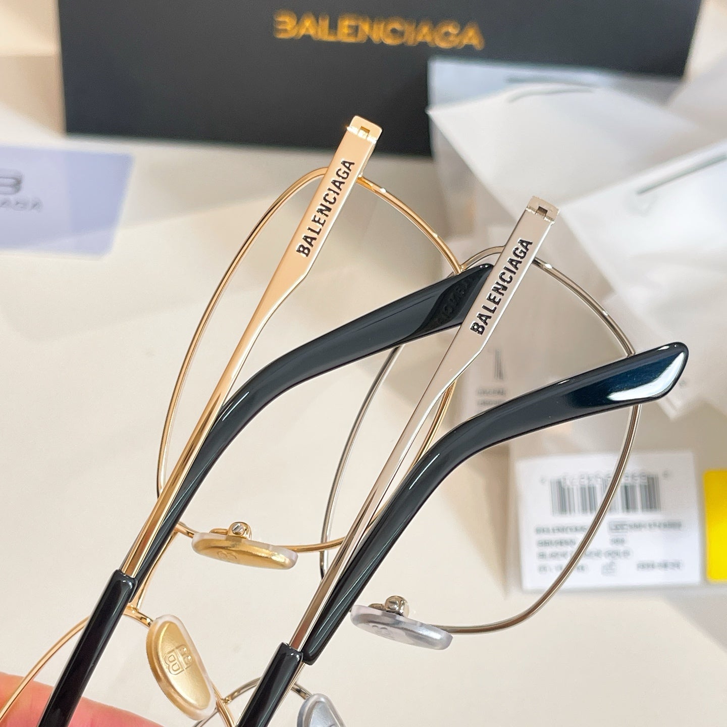 Two Balenciaga eyeglasses with gold frames and dark blue temple accents