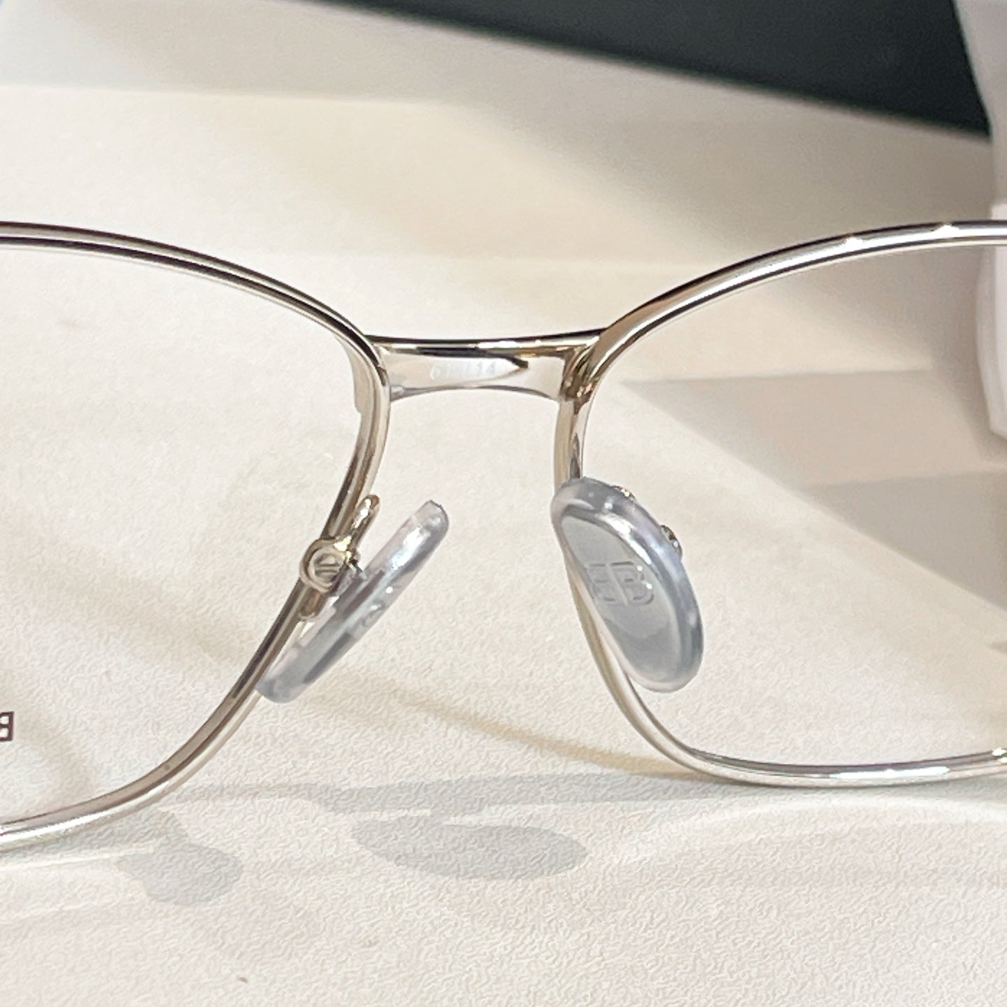 Balenciaga glasses close-up with clear lenses, gold bridge, and metal nose pads