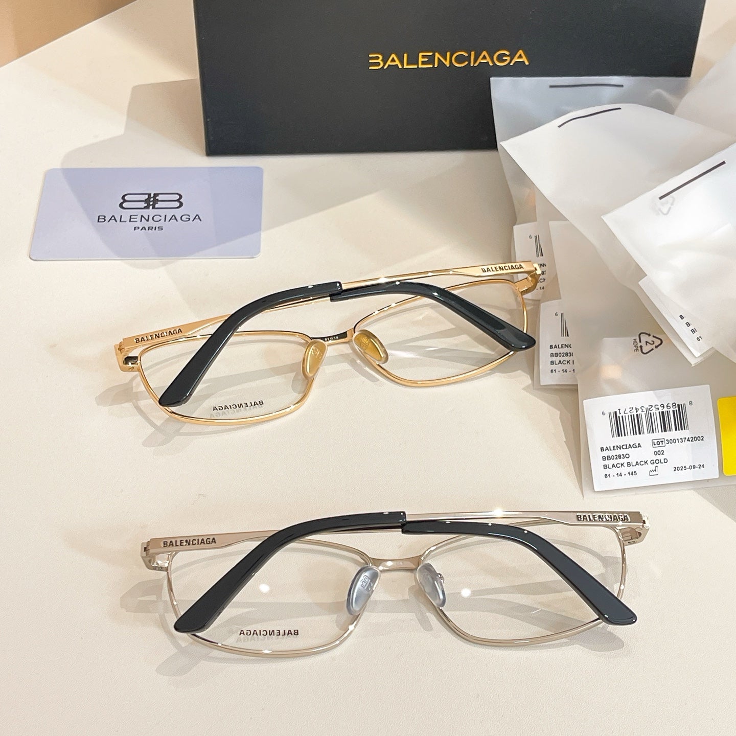 Two Balenciaga eyeglasses with gold-and-dark frames and clear lenses