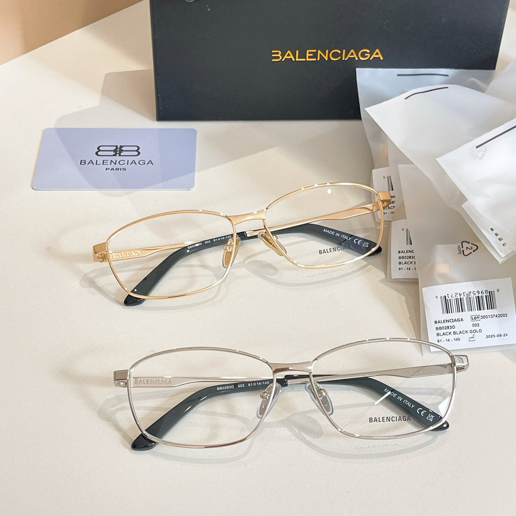 Two Balenciaga eyeglasses with gold frames and dark blue temple details