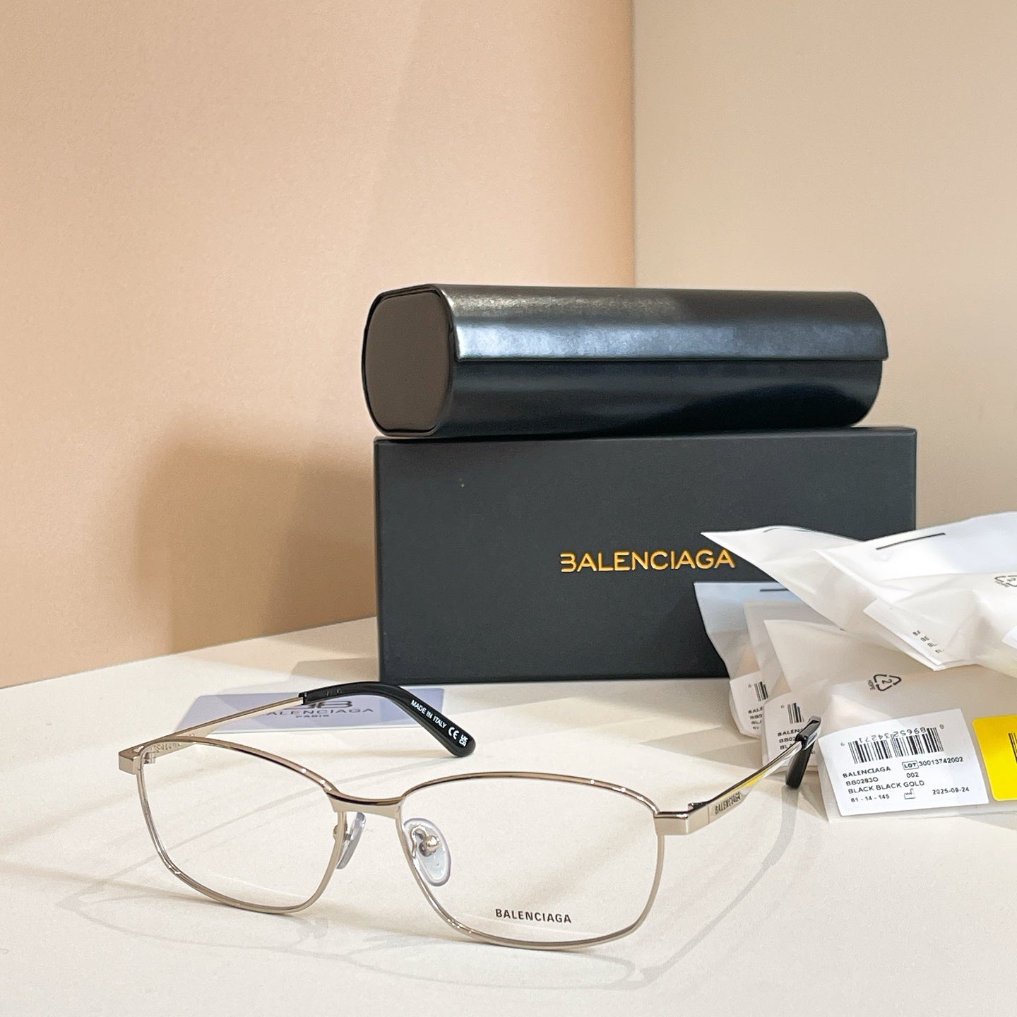 Balenciaga glasses with gold full-rim frames, clear lenses, and dark blue temples