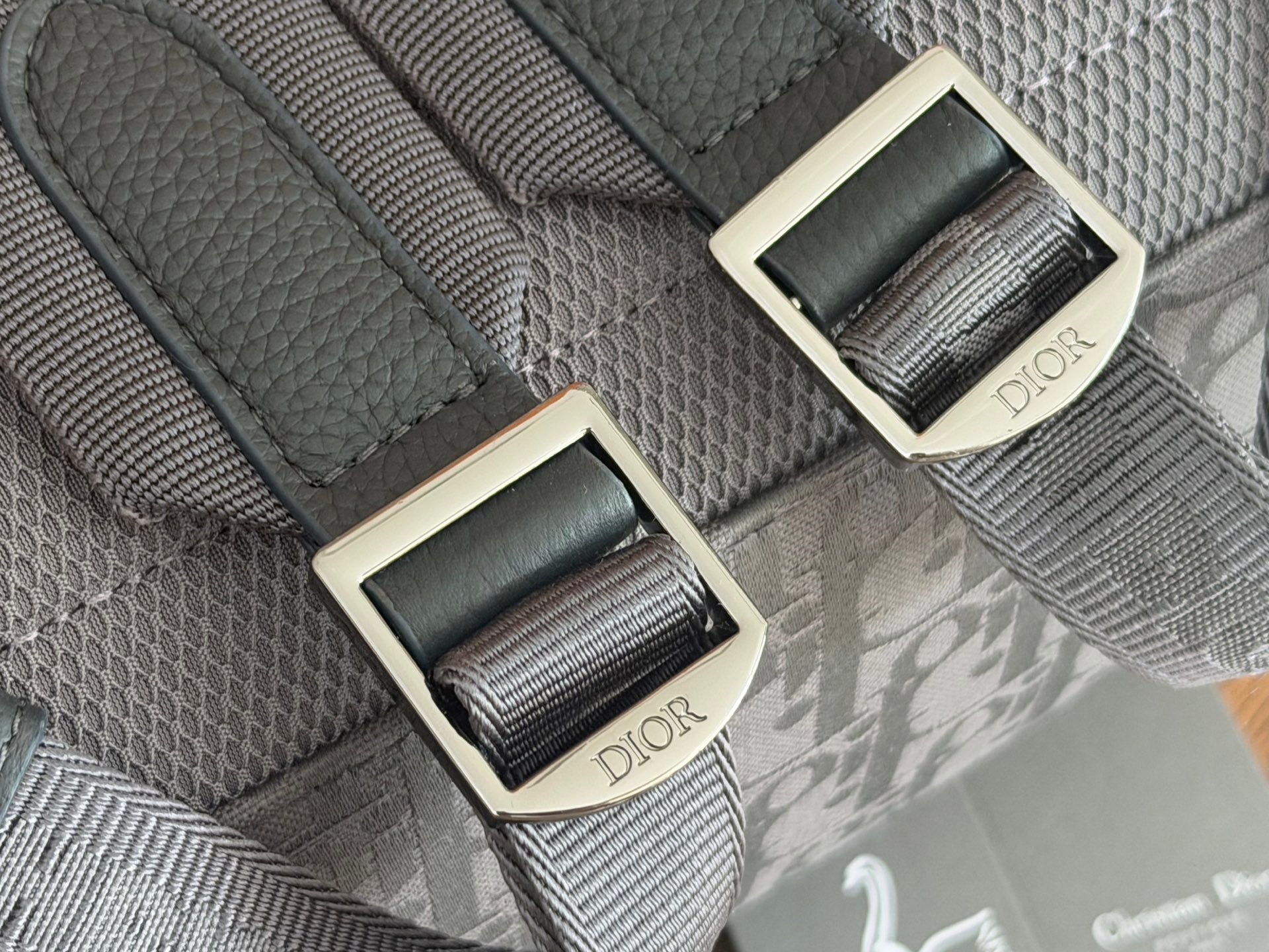 Dior men’s backpack close-up of strap adjusters with Dior-branded leather tabs