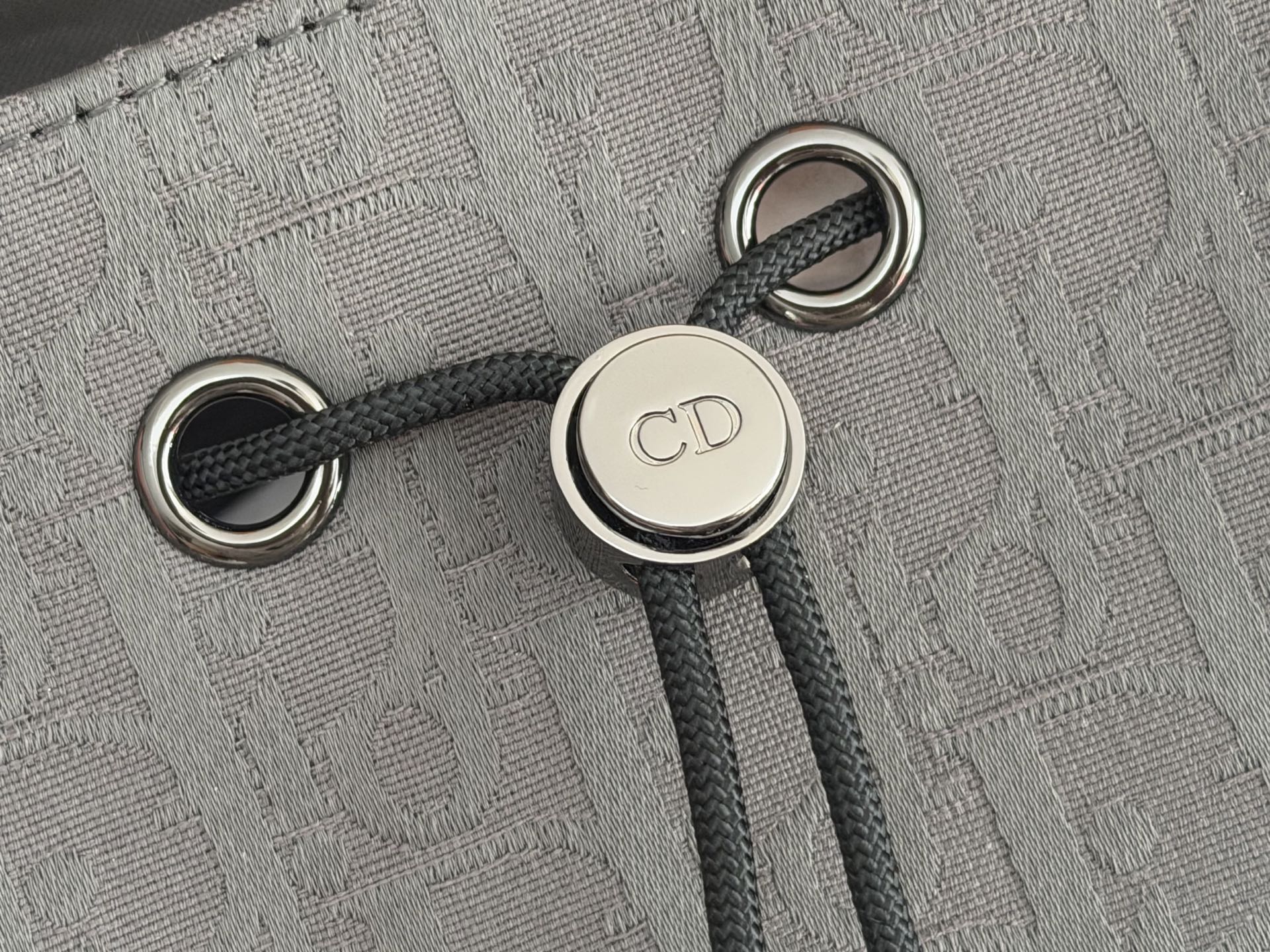 Dior men’s backpack close-up of drawstring eyelets and CD logo button hardware