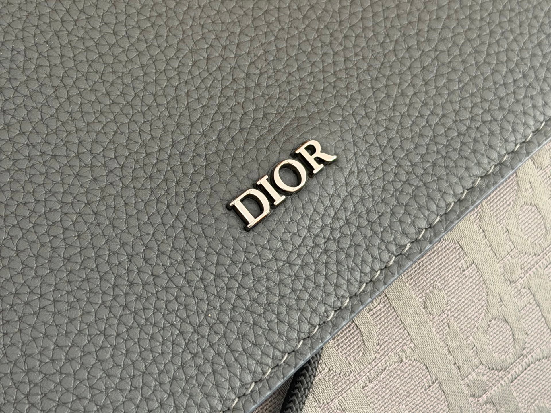 Dior men’s backpack close-up of dark gray leather with DIOR embossed logo