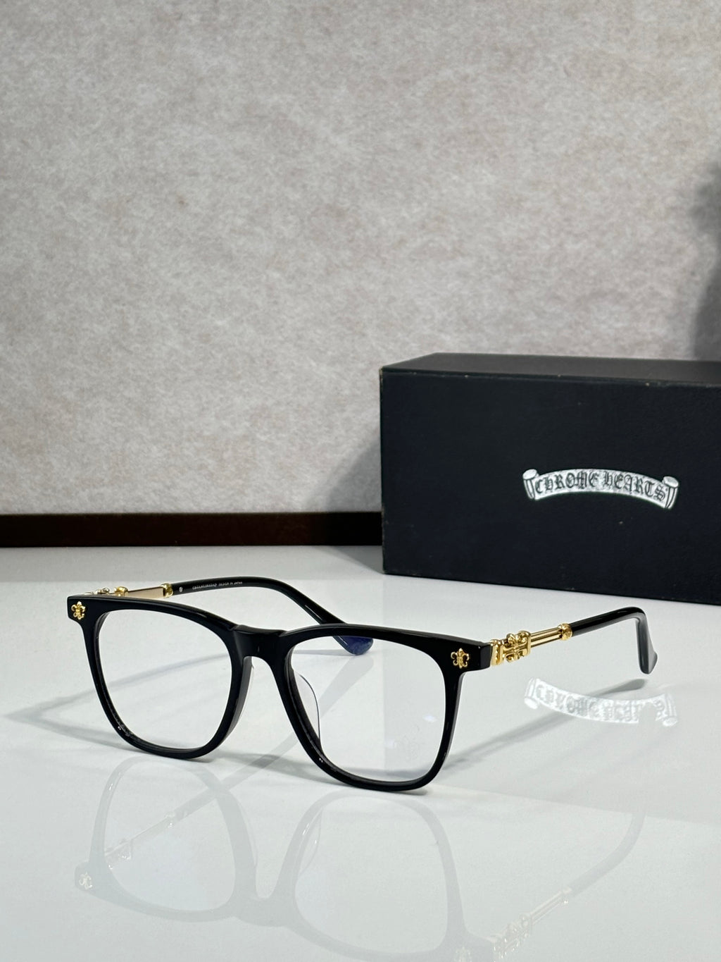 Black full-rim eyeglasses with clear lenses and gold detail temples