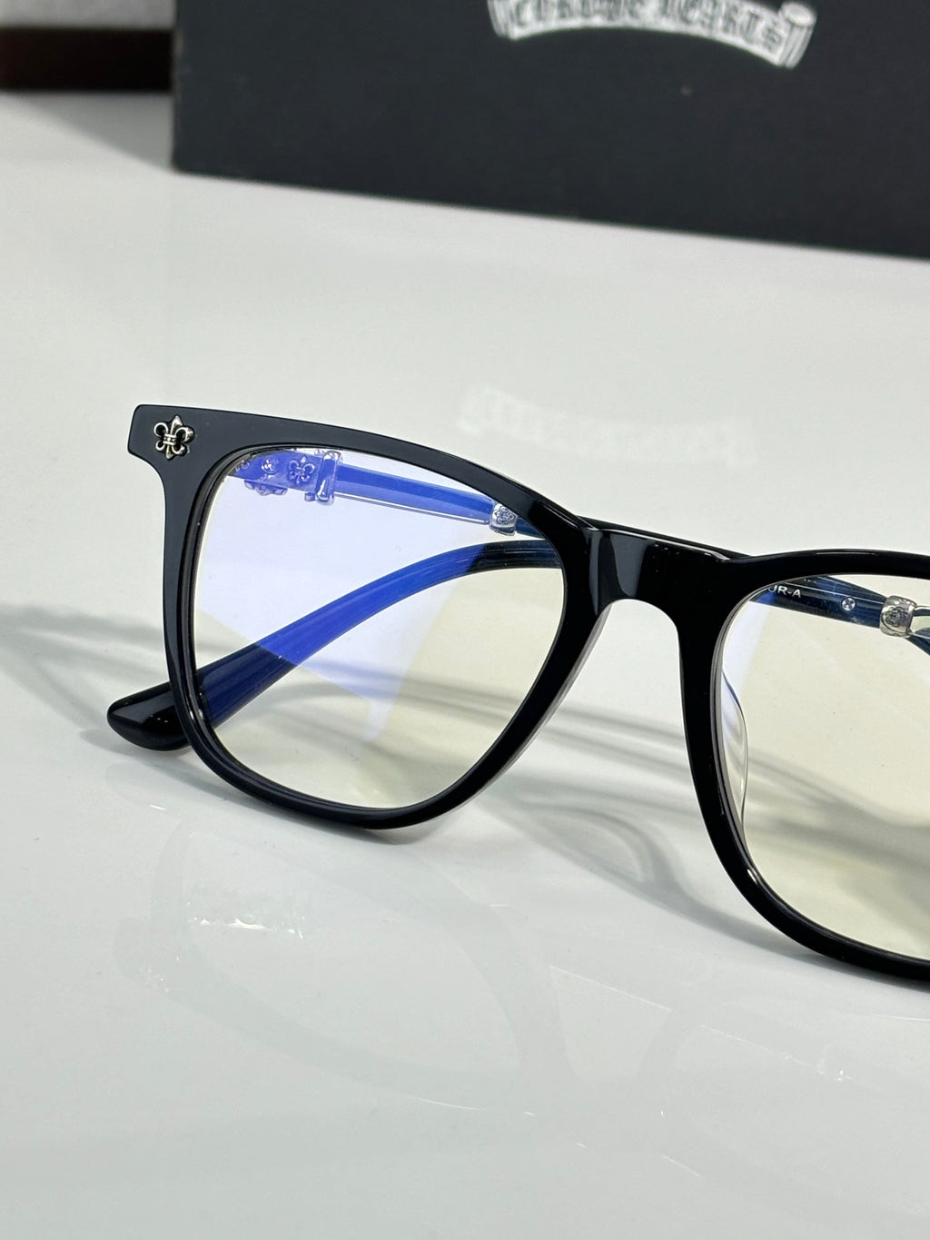 Close-up black full-rim eyeglasses with blue-tinted lens and metal temple