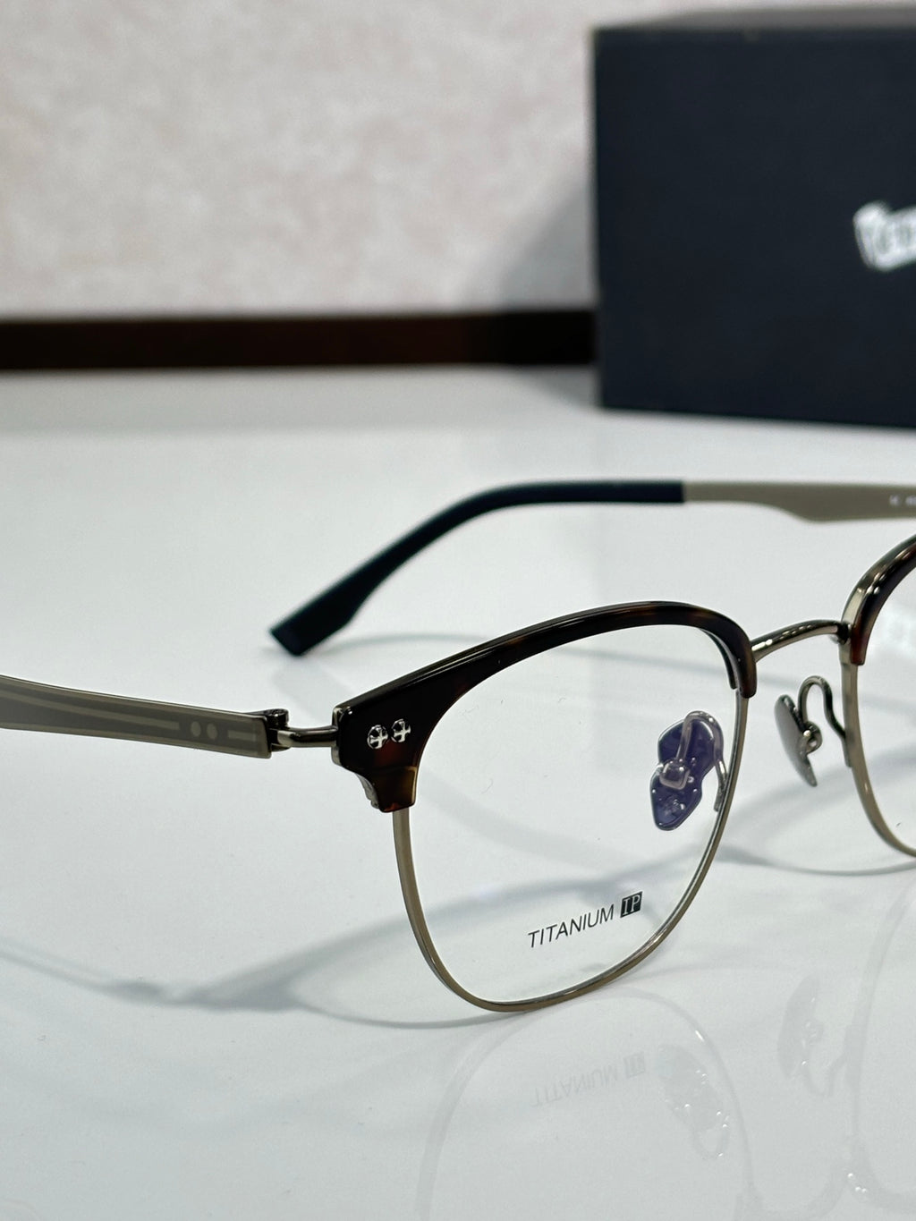 Eyeglasses close-up with dark metal frame, clear lenses, side temple details