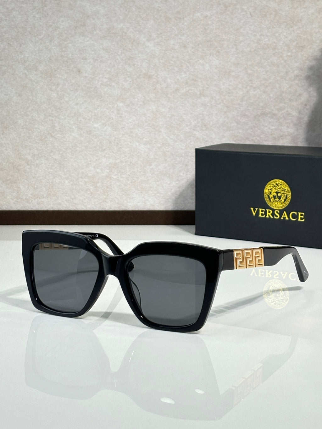 Versace eyeglasses with black frames, dark lenses, gold temple badge on side.