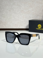 Versace eyeglasses with black frames and dark lenses, patterned interior detail.
