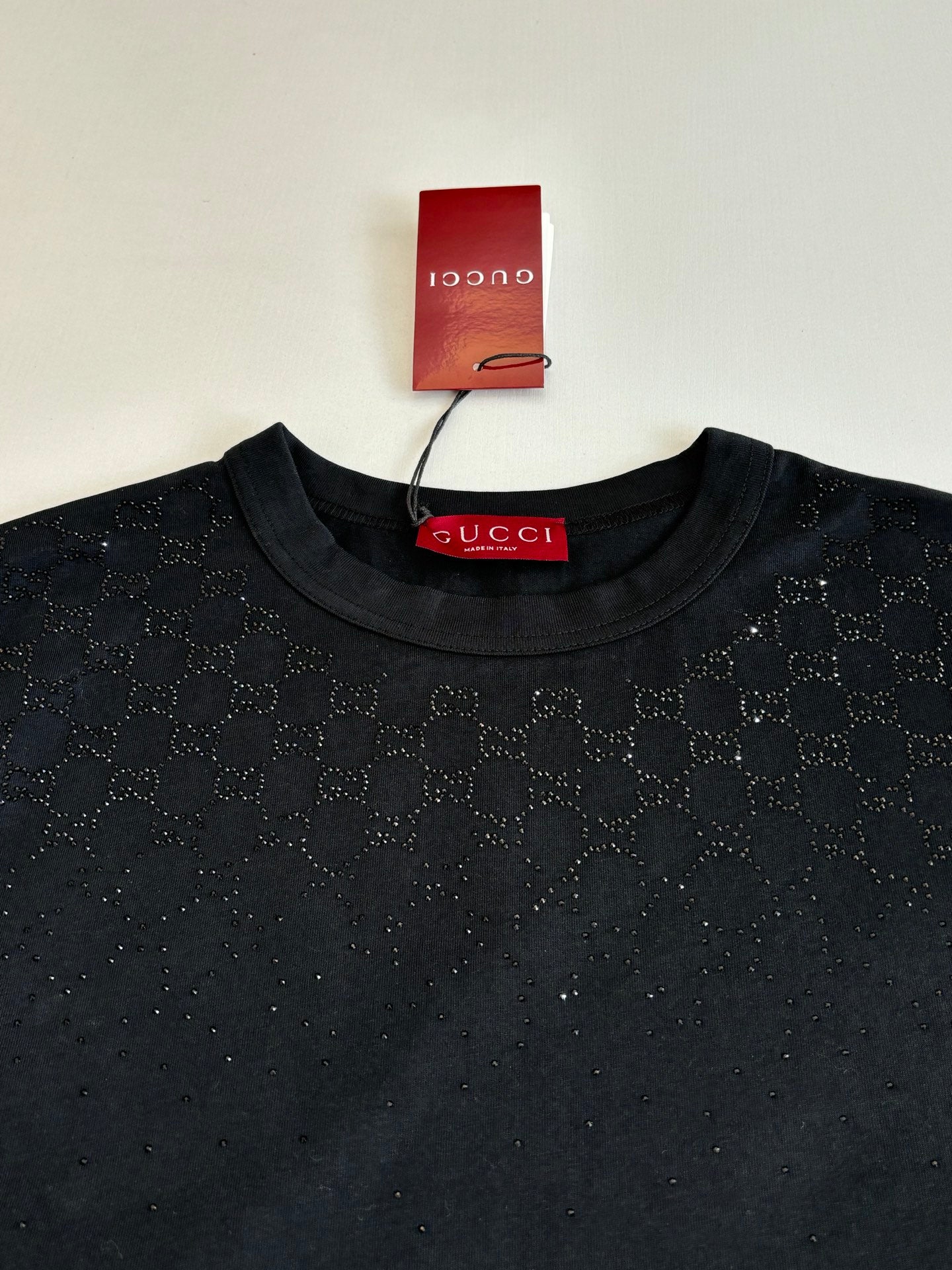 Black short-sleeve T-shirt close-up: crew neck with Gucci label, all-over pattern
