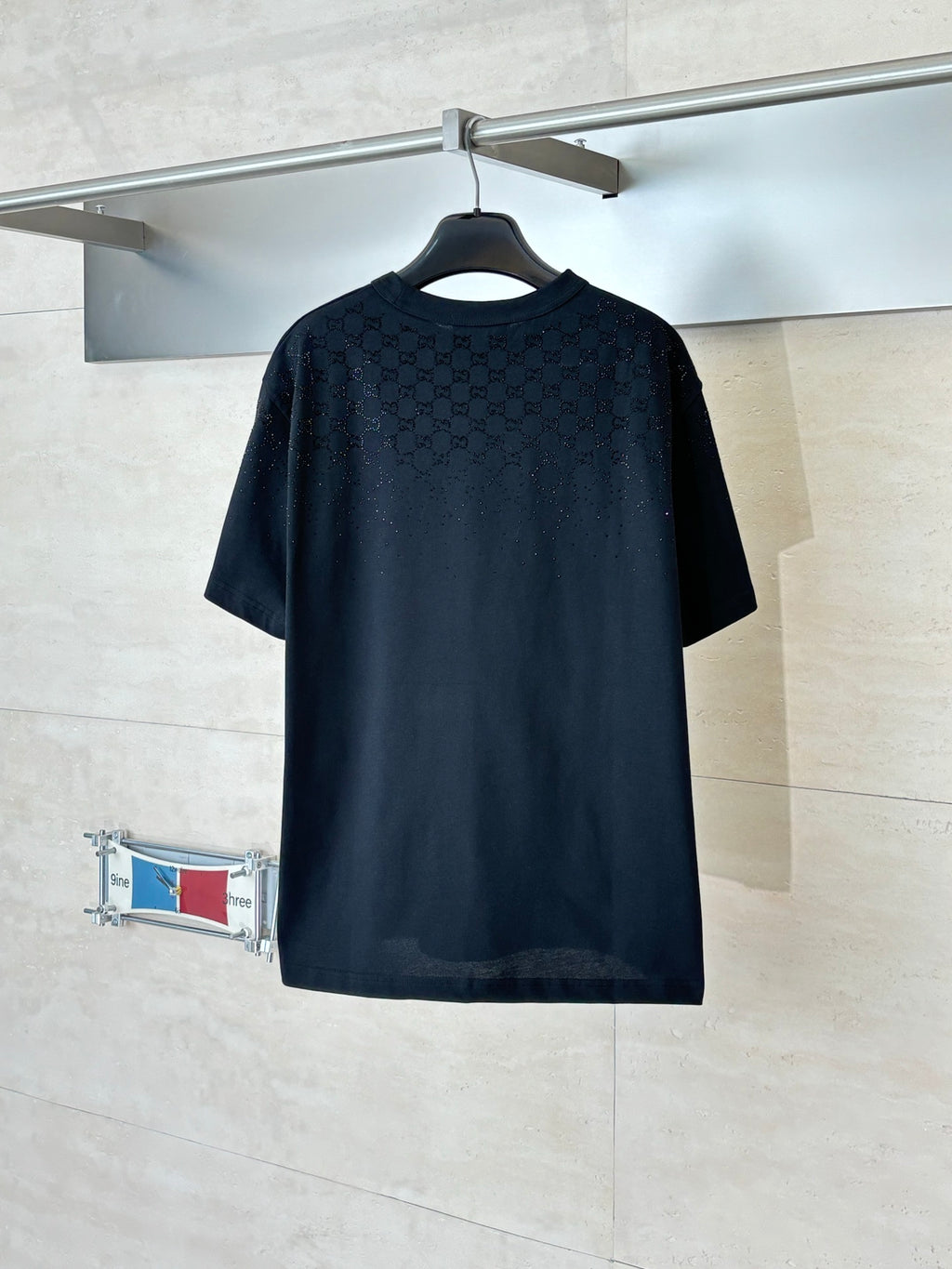 Black short-sleeve T-shirt with subtle all-over pattern, crew neck, back view on hanger