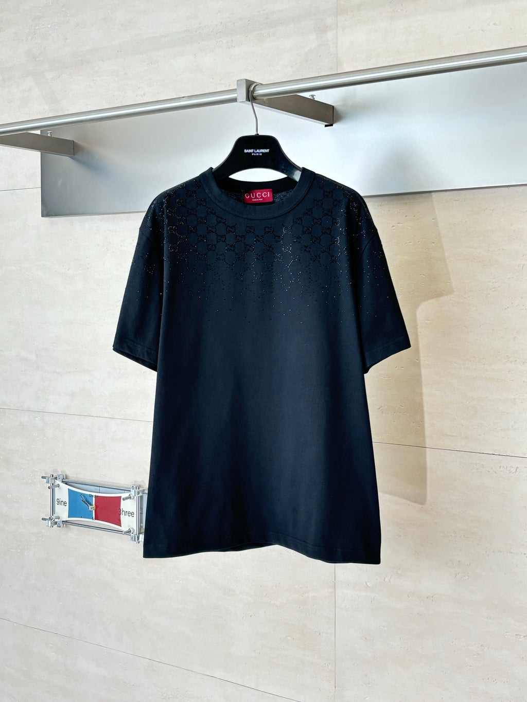 Black short-sleeve T-shirt with subtle all-over pattern, crew neck, on a hanger