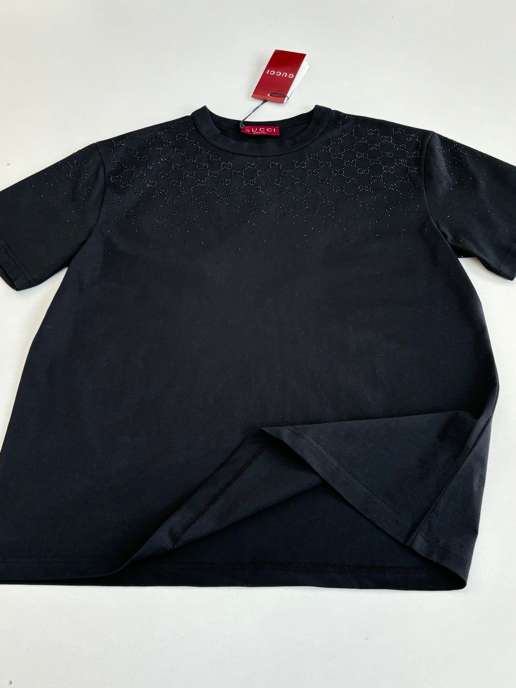 Black short-sleeve T-shirt laid flat with red Gucci neck label