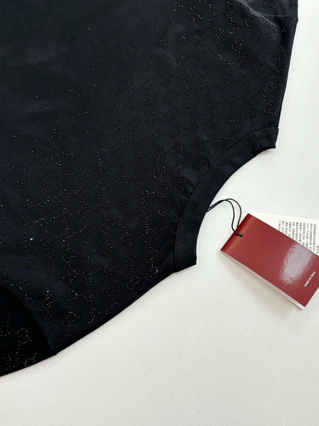 Black short-sleeve T-shirt torso with red Gucci tag on a white surface
