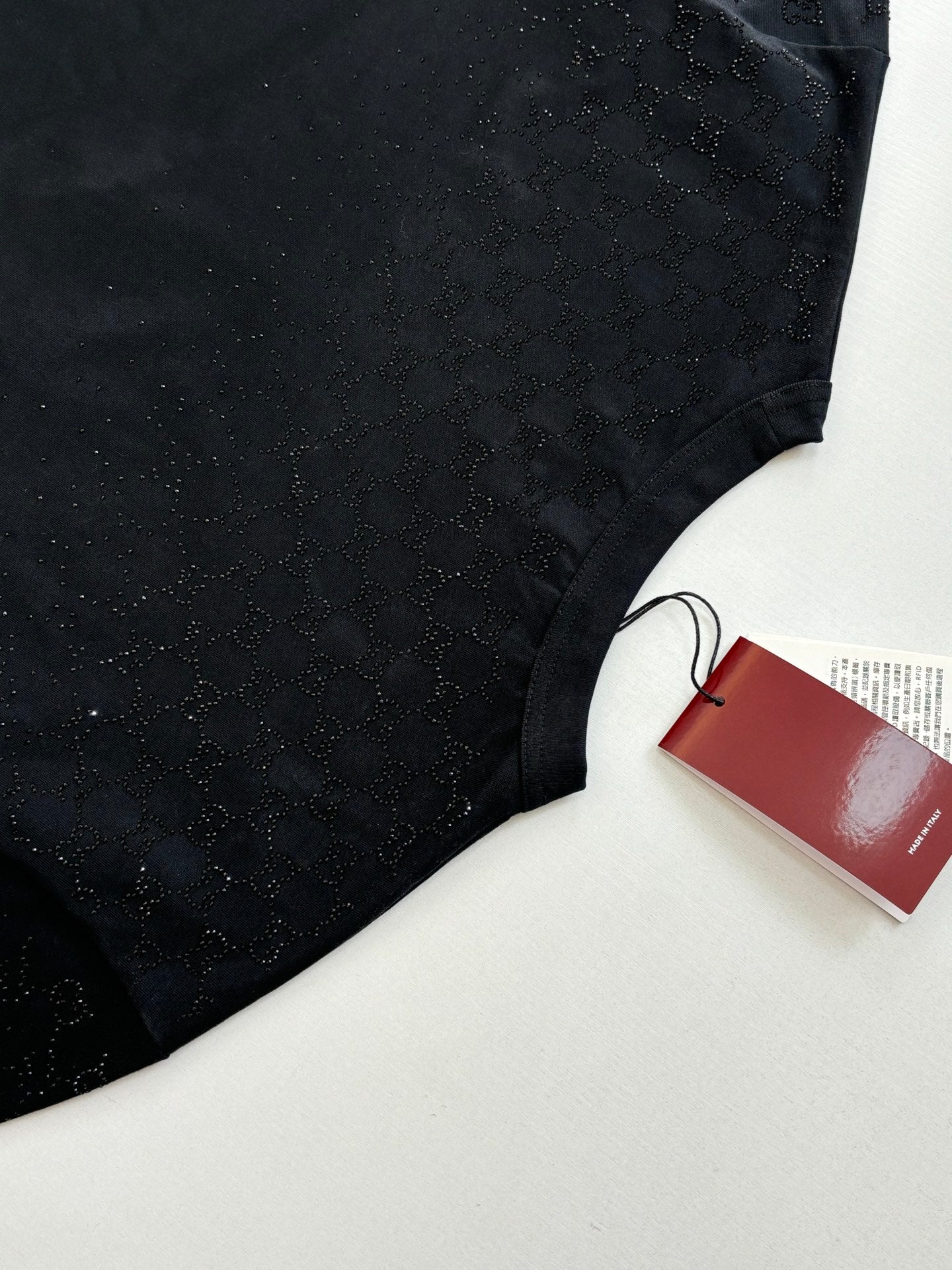 Black short-sleeve T-shirt torso with red Gucci tag on a white surface