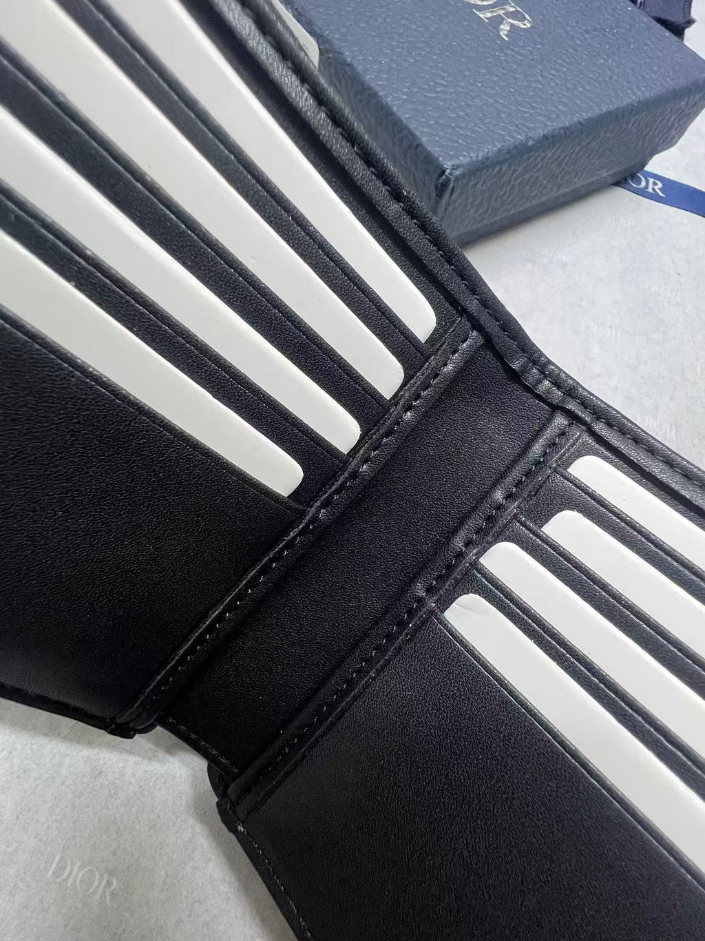 Small bag wallet detail with black leather edges and white card slot openings.