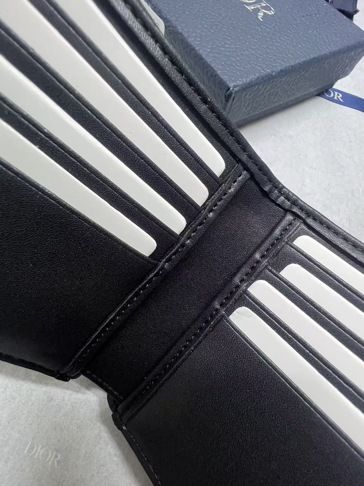 Small bag wallet detail with black leather edges and white card slot openings.