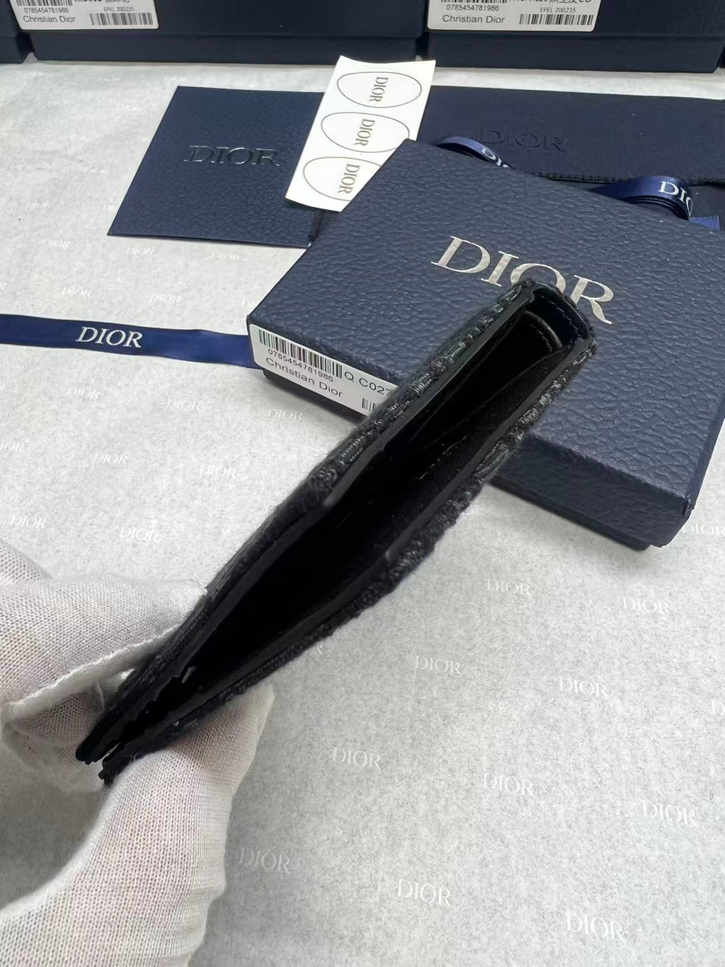 Small bag with black interior, navy Dior logo exterior and zippered opening.