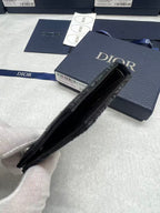 Small bag with black interior, navy Dior logo exterior and zippered opening.