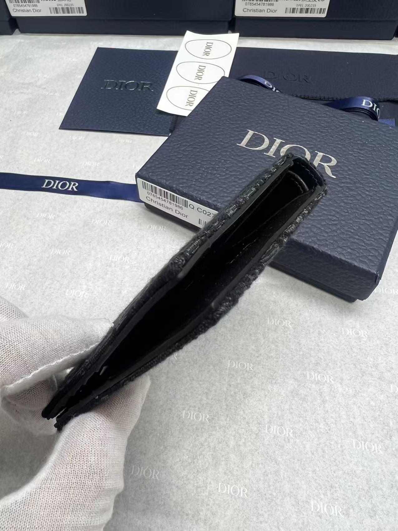 Small bag with black interior, navy Dior logo exterior and zippered opening.