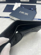 Small leather card holder with black interior and Dior logo, open view.