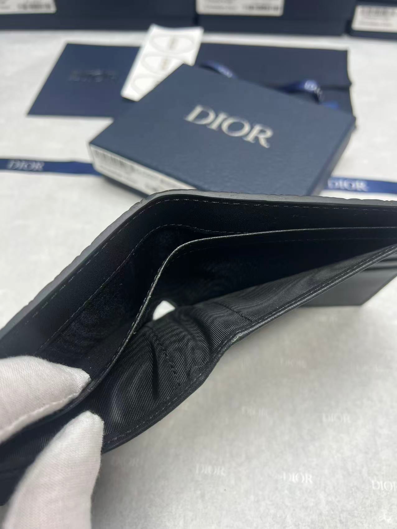 Small leather card holder with black interior and Dior logo, open view.