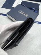 Small leather card holder with black fold and Dior branding, side view.