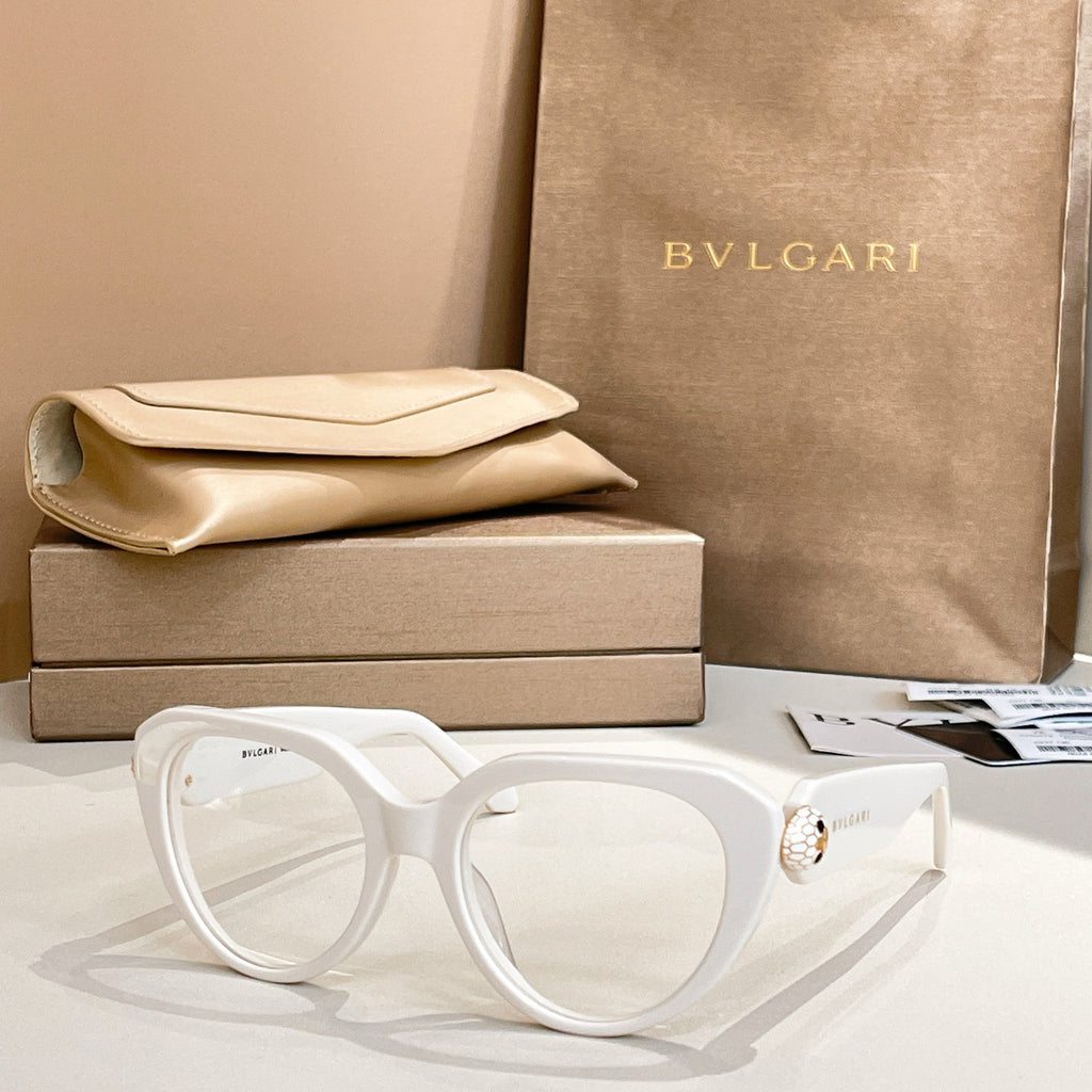 White round eyeglasses with thick frame and gold logo emblem on temple.