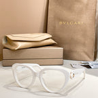 White round eyeglasses with thick frame and gold logo emblem on temple.