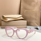 Light pink round eyeglasses with thick frame and gold logo emblem on temple.