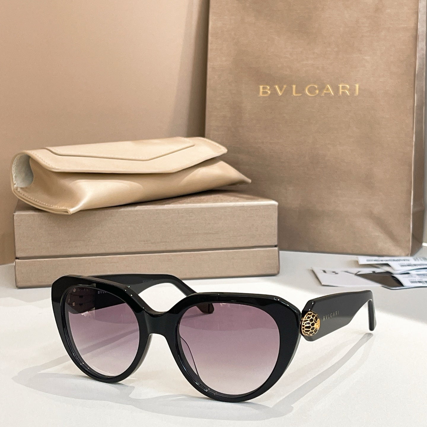 Black round eyeglasses with thick frame, gold logo detail on temple.