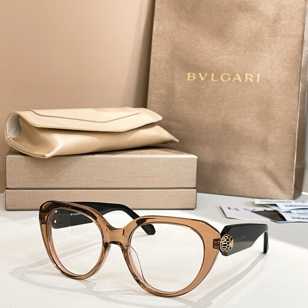 Brown round eyeglasses with thick frame and gold logo emblem on side.