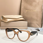 Brown round eyeglasses with thick frame and gold logo emblem on side.