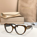Tortoiseshell round eyeglasses with thick frame, gold logo emblem on temple.