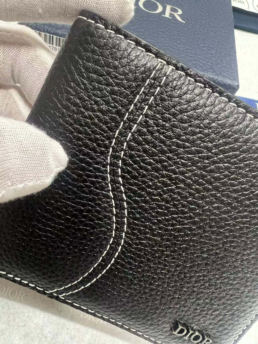 Black leather small wallet close-up with stitched curved seam and Dior logo