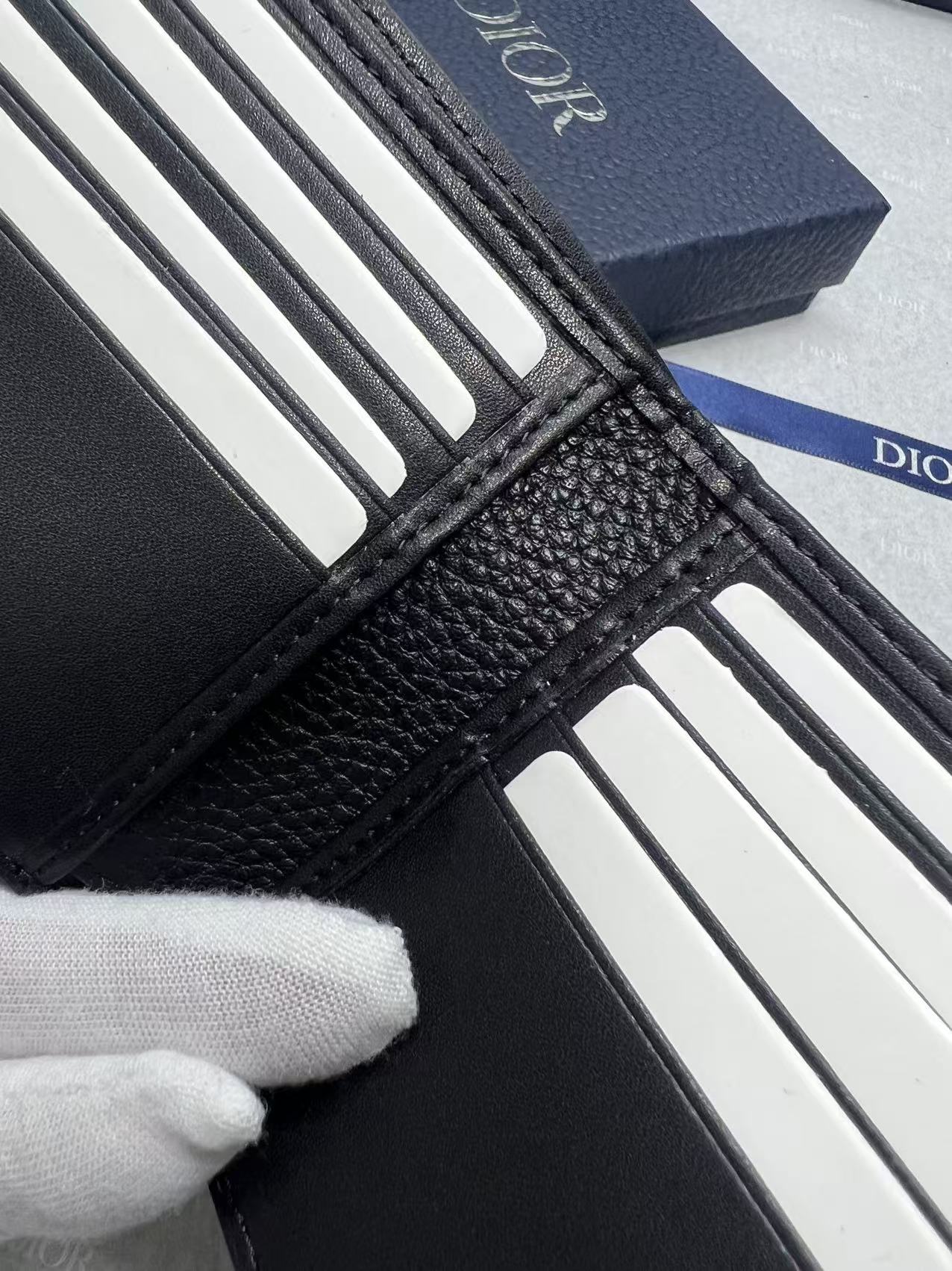 Small leather card holder corner with card slots and black textured trim, Dior branding.