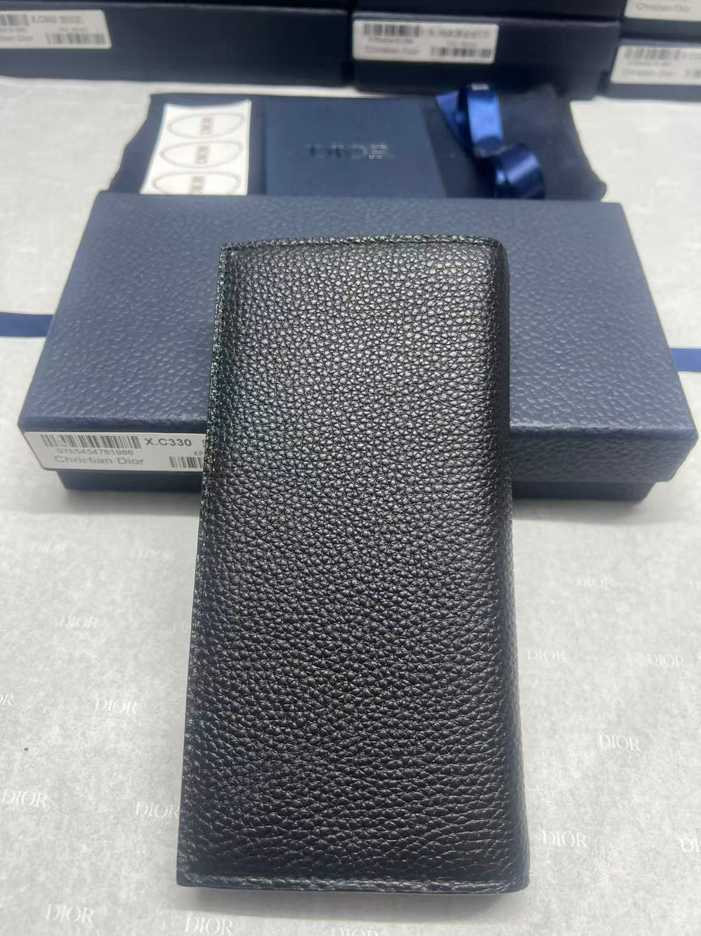 Black textured leather wallet, vertical front with embossed logo detail