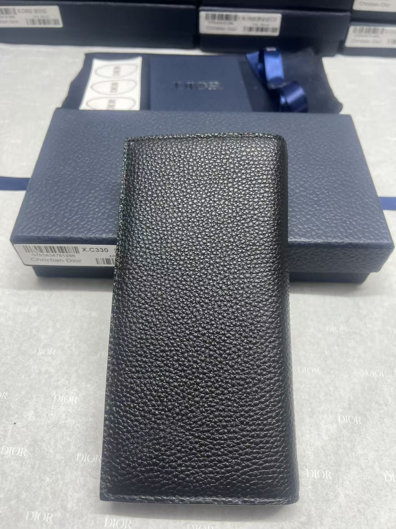 Black textured leather wallet, vertical front with embossed logo detail