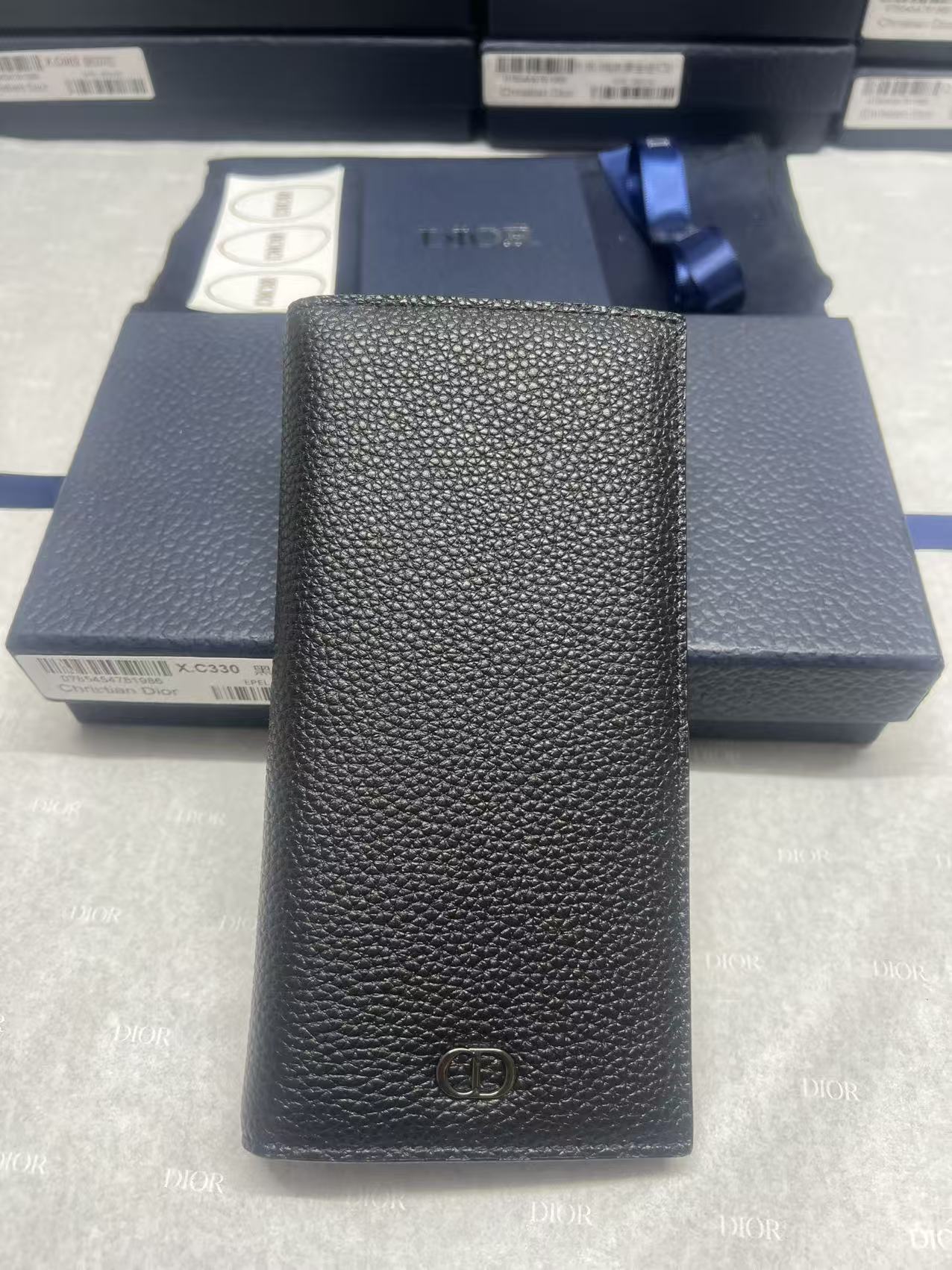 Black textured leather wallet with central embossed logo, vertical front