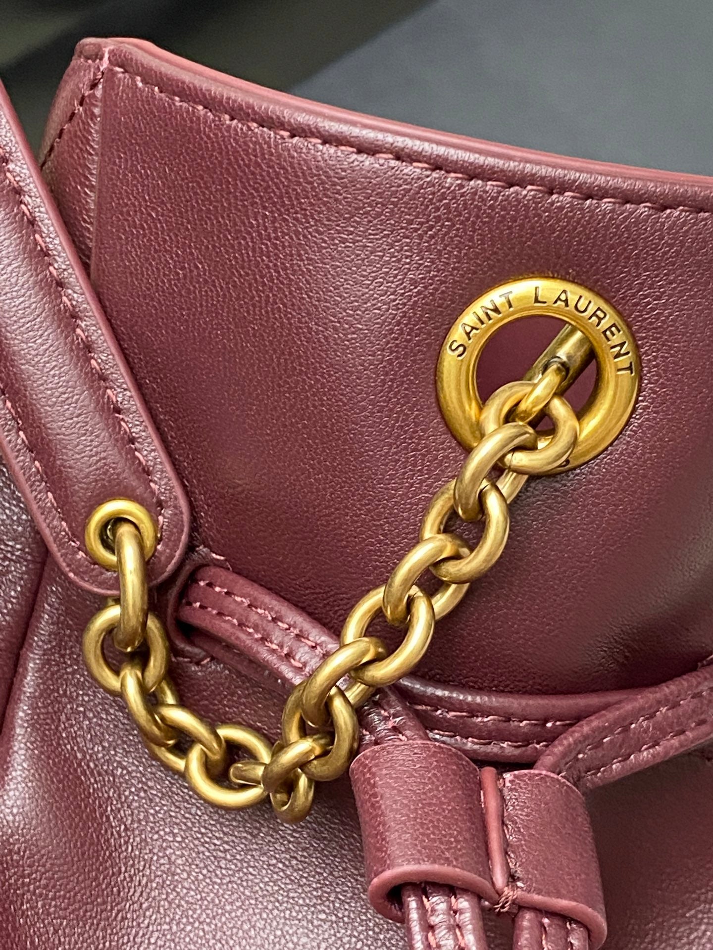 YSL pink leather bag detail with gold chain, Saint Laurent emblem, and stitching